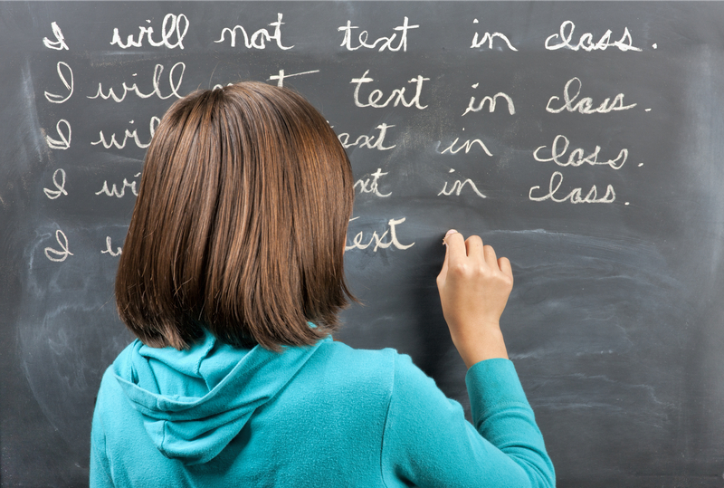 girl writes on blackboard in cursive