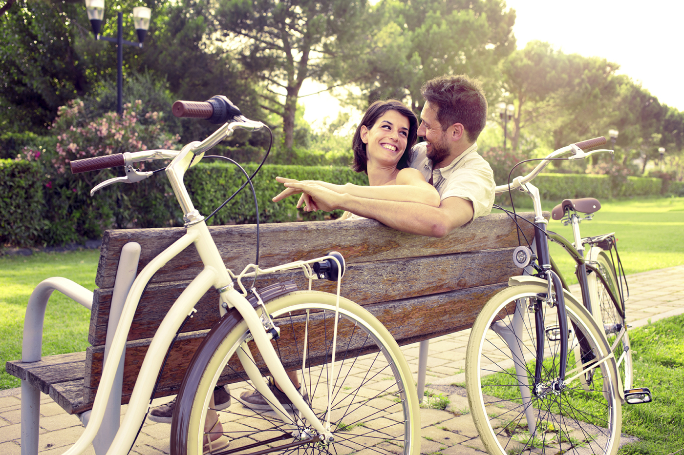 Couple in love sitted togheter on a bench with bikes beside
