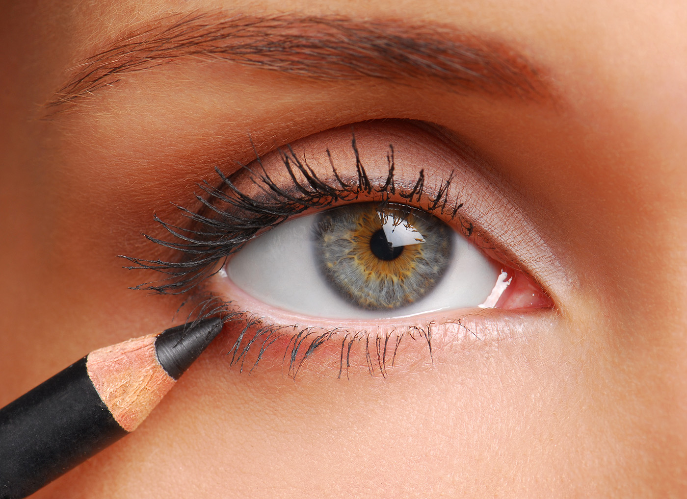 woman applying black eyeliner waterline