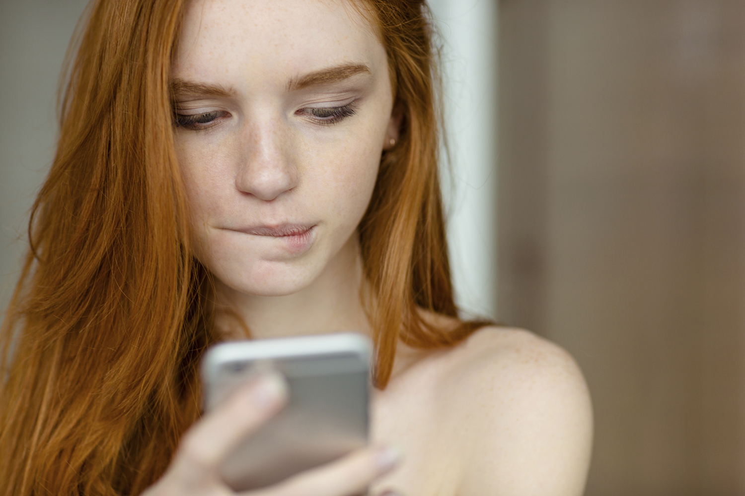 Closeup portrait of a beautiful redhead woman using smartphone