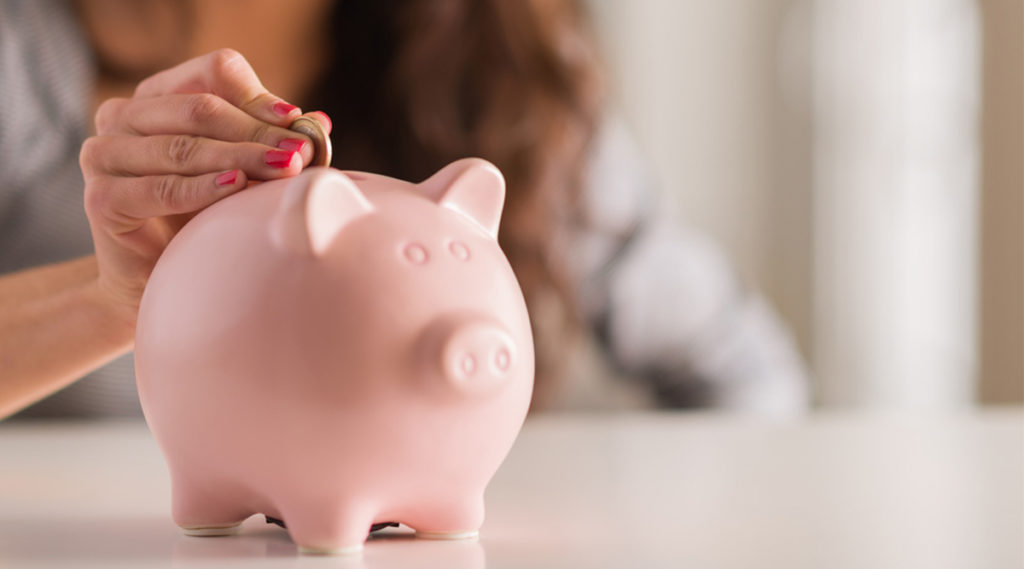 woman putting coin in piggy bank