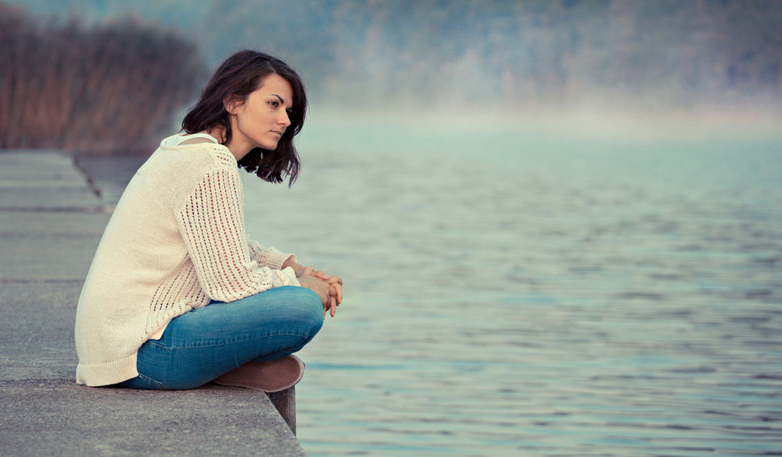 woman sitting by a lake