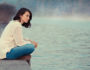 woman sitting by a lake